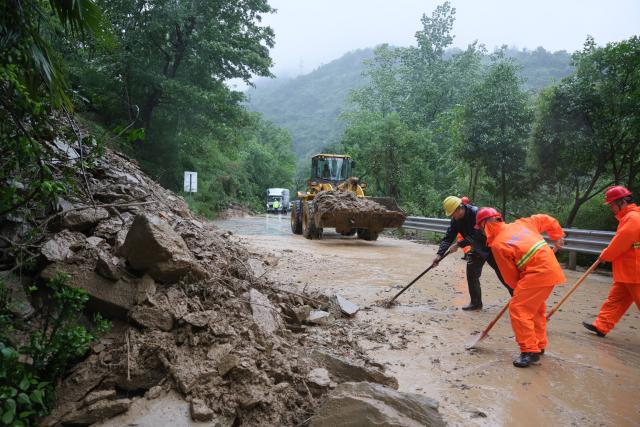 (260812) -- XIANGYANG, Aug. 12, 2026 (Xinhua) -- Staff members remove collapsed rocks from the section of the G241 national highway in Baokang County of Xiangyang City, central China's Hubei Province, Aug. 12, 2026. Torrential rains and flooding caused by Typhoon Dolphin, the 13th typhoon of the year, have swept vast regions in eastern and central China. Local authorities are exerting all efforts to eradicate potential risks and put people's life back to normal. (Photo by Yang Dong/Xinhua)
