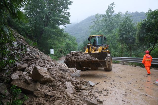 (260812) -- XIANGYANG, Aug. 12, 2026 (Xinhua) -- A maintenance worker operates an engineering machine to remove collapsed rocks from the section of the G241 national highway in Baokang County of Xiangyang City, central China's Hubei Province, Aug. 12, 2026. Torrential rains and flooding caused by Typhoon Dolphin, the 13th typhoon of the year, have swept vast regions in eastern and central China. Local authorities are exerting all efforts to eradicate potential risks and put people's life back to normal. (Photo by Yang Dong/Xinhua)