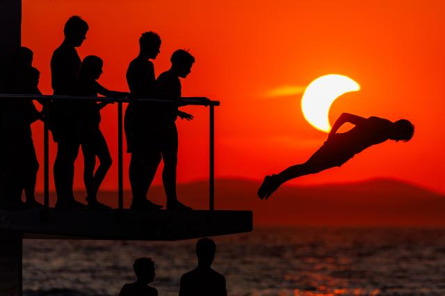 (260812) -- ZADAR, Aug. 12, 2026 (Xinhua) -- People queue to dive at Kolovare Beach as the moon partially covers the sun during a solar eclipse in Zadar, Croatia, Aug. 12, 2026. (Zvonimir Barisin/PIXSELL via Xinhua)