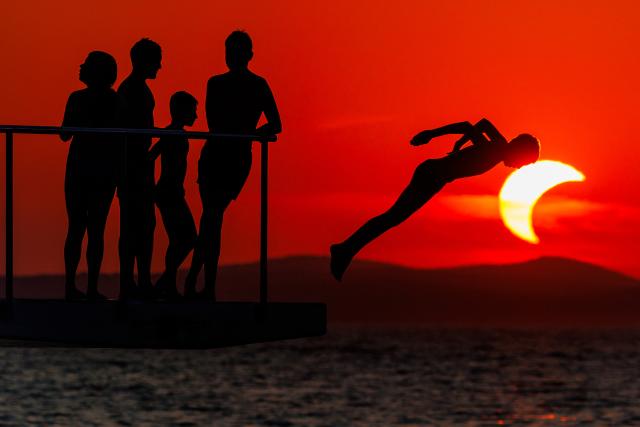 (260812) -- ZADAR, Aug. 12, 2026 (Xinhua) -- People queue to dive at Kolovare Beach as the moon partially covers the sun during a solar eclipse in Zadar, Croatia, Aug. 12, 2026. (Zvonimir Barisin/PIXSELL via Xinhua)
