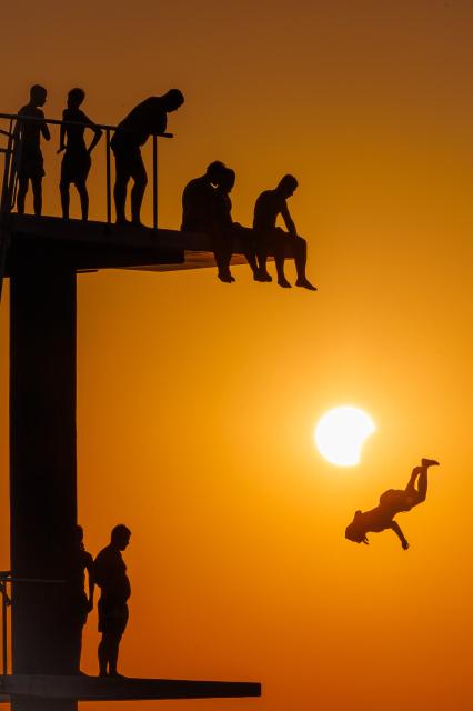 (260812) -- ZADAR, Aug. 12, 2026 (Xinhua) -- People queue to dive at Kolovare Beach as the moon partially covers the sun during a solar eclipse in Zadar, Croatia, Aug. 12, 2026. (Zvonimir Barisin/PIXSELL via Xinhua)