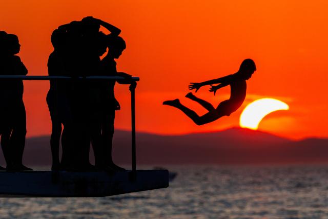 (260812) -- ZADAR, Aug. 12, 2026 (Xinhua) -- People queue to dive at Kolovare Beach as the moon partially covers the sun during a solar eclipse in Zadar, Croatia, Aug. 12, 2026. (Zvonimir Barisin/PIXSELL via Xinhua)