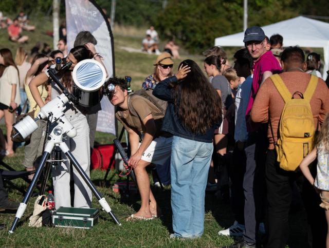 (260812) -- BERLIN, Aug. 12, 2026 (Xinhua) -- People queue up to try out the observation equipment at the Zeiss Grand Planetarium in Berlin, Germany, Aug. 12, 2026. The Long Night of Astronomy event was held here on Wednesday, inviting the public to observe the solar eclipse and experience the fascination of astronomy. (Xinhua/Zhang Haofu)