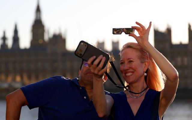(260812) -- LONDON, Aug. 12, 2026 (Xinhua) -- People pose for selfies during a partial solar eclipse in London, Britain, Aug. 12, 2026. (Xinhua/Li Ying)