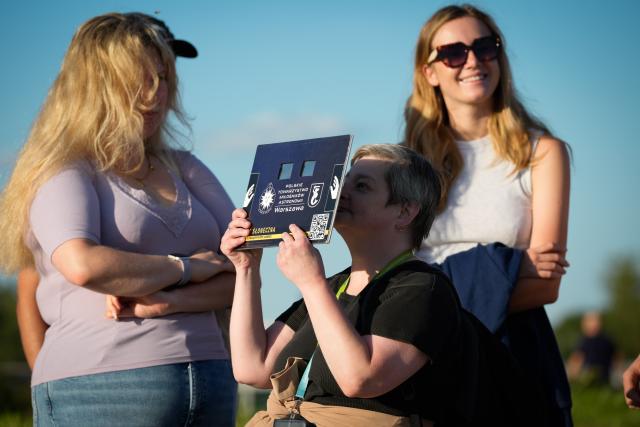 (260813) -- WARSAW, Aug. 13, 2026 (Xinhua) -- A woman (C) uses solar eclipse glasses to observe the partial solar eclipse at the Copernicus Science Center in Warsaw, Poland, Aug. 12, 2026. (Photo by Jaap Arriens/Xinhua)