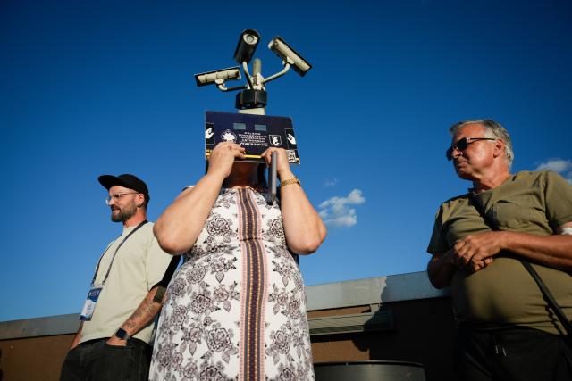 (260813) -- WARSAW, Aug. 13, 2026 (Xinhua) -- A woman (C) uses solar eclipse glasses to observe the partial solar eclipse at the Copernicus Science Center in Warsaw, Poland, Aug. 12, 2026. (Photo by Jaap Arriens/Xinhua)