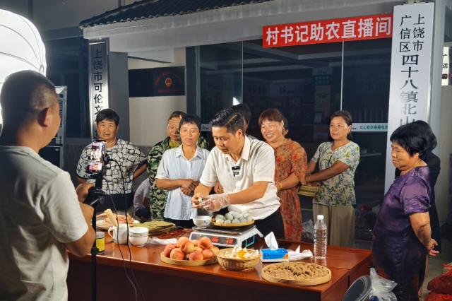 (260813) -- NANCHANG, Aug. 13, 2026 (Xinhua) -- Chen Jianguo (C, front), Party secretary of Beishan Village, promotes agricultural products at a livestream session in Beishan Village of Guangxin District in Shangrao City, east China's Jiangxi Province, July 10, 2025.
  Chen Jianguo, Party secretary of Beishan Village, opened social media accounts to post farm produce promotion clips and leveraged livestreaming to sell local agricultural products. Villagers pack their produce up to his livestream sessions one after another, creating a bustling scene similar as open-air markets.
  As e-commerce is increasingly employed to boost farmers' incomes, Party members and village officials are mobilized to participate actively in livestreaming sales, leading the way in navigating this new path to prosperity. (Photo by Zheng Hanlin/Xinhua)