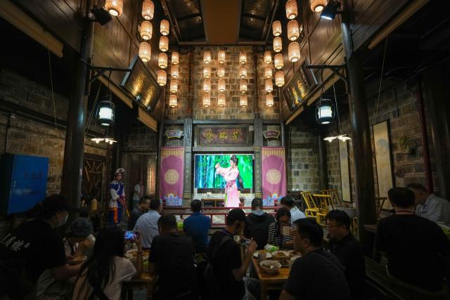 (260813) -- YIYANG, Aug. 13, 2026 (Xinhua) -- Tourists watch a local opera performance at a tea house within a historic and cultural district in Yiyang City, central China's Hunan Province, on Aug. 12, 2026.
  The old district dating back to the Ming and Qing dynasties (1368-1911) is home to 41 cultural heritage sites. 
  As the nighttime economy continues to gain momentum during the summer vacation, the district is attracting large numbers of visitors with its diverse tourism offerings. The passenger flow at night now accounts for 65 percent of the district's total daily visits, while nighttime spending makes up 70 percent of total consumption. (Xinhua/Dai Mingxuan)