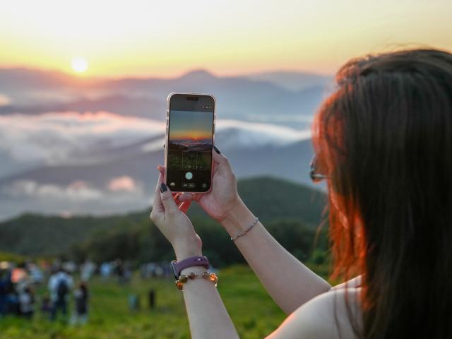 (260813) -- JILIN, Aug. 13, 2026 (Xinhua) -- A tourist takes photos of sunrise at the Lake Songhua Resort in Jilin City, northeast China's Jilin Province, Aug. 12, 2026. The Lake Songhua Resort, located in Jilin City, is a national-level ski tourism resort. In recent years, relying on its mountain resources, the resort has extended operation in other seasons except for winter, attracting tourists with natural scenery and mountain sports. 
   Since April 25 this year, the resort has received a total of 200,000 visitors, a year-on-year growth of 20 percent. From popular destination in winter to year-round operation, the tourism potential of the resort is being fully tapped, promoting the high-quality development of the local cultural and tourism industry. (Xinhua/Zhang Nan)