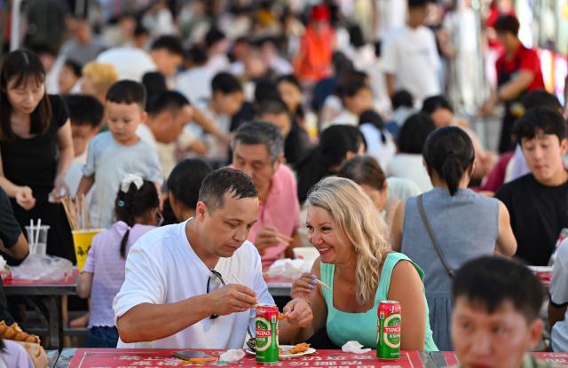 (260813) -- HAIKOU, Aug. 13, 2026 (Xinhua) -- Tourists enjoy local delicacies at a night market in Haikou, south China's Hainan Province, July 17, 2026. Hainan is stepping up with efforts to build a world-class destination for international tourism and consumption as a key component of the Hainan Free Trade Port, and to probe for a new path towards high-quality development in its tourism-led consumer economy with distinctive local characteristics. 
   Hainan is projected to annually receive 154 million counts of domestic and international visits by 2030, along with tourism-related revenue of 363 billion yuan (about 53.83 billion U.S. dollars). (Xinhua/Guo Cheng)
