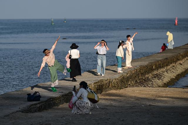 (260813) -- HAIKOU, Aug. 13, 2026 (Xinhua) -- Tourists have fun near Tanmen Port in Qionghai, south China's Hainan Province, July 24, 2026. Hainan is stepping up with efforts to build a world-class destination for international tourism and consumption as a key component of the Hainan Free Trade Port, and to probe for a new path towards high-quality development in its tourism-led consumer economy with distinctive local characteristics. 
   Hainan is projected to annually receive 154 million counts of domestic and international visits by 2030, along with tourism-related revenue of 363 billion yuan (about 53.83 billion U.S. dollars). (Xinhua/Pu Xiaoxu)