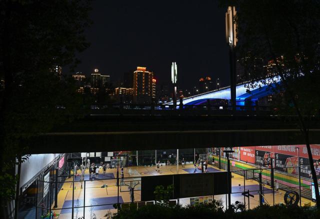 (260814) -- CHONGQING, Aug. 14, 2026 (Xinhua) -- Residents play basketball under a bridge in Liangjiang New Area, southwest China's Chongqing, Aug. 12, 2026. In recent years, Liangjiang New Area has transformed vacant spaces under bridges into spaces for exercise and recreation. (Xinhua/Chen Cheng)