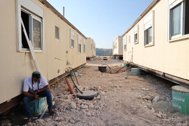 (260814) -- JERUSALEM, Aug. 14, 2026 (Xinhua) -- A Jewish settler sits near prefabricated houses in the West Bank settlement of Ganim on Aug. 13, 2026.
  Four settlements in the West Bank, including Ganim, were evacuated in 2005 as part of Israel's "Disengagement Plan". The Ganim settlement has now been re-established, 21 years after its evacuation. (Photo by Gil Cohen Magen/Xinhua)