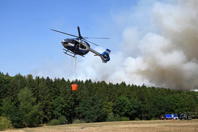(260814) -- GEY, Aug. 14, 2026 (Xinhua) -- A helicopter fetches water to extinguish a wildfire in Gey, Germany, Aug. 14, 2026. According to German media reports, a wildfire broke out in North Rhine-Westphalia, and over 2,000 residents were evacuated as a precaution for safety reasons. (Photo by Ulrich Hufnagel/Xinhua)