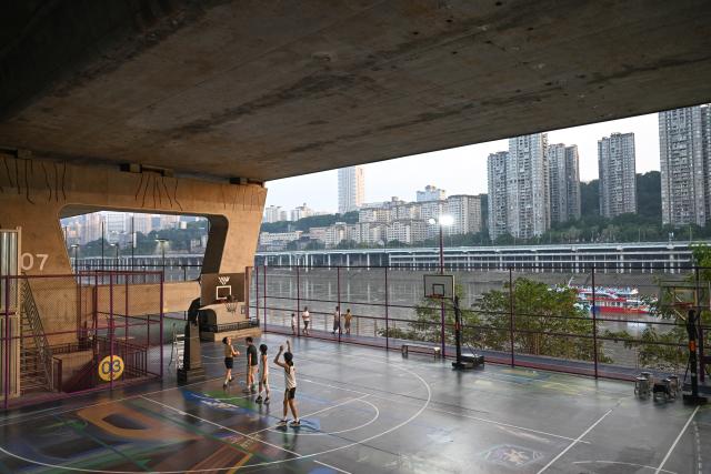 (260815) -- BEIJING, Aug. 15, 2026 (Xinhua) -- Residents play basketball under a bridge in Liangjiang New Area, southwest China's Chongqing, Aug. 10, 2026. In recent years, Liangjiang New Area has transformed vacant spaces under bridges into spaces for exercise and recreation. (Xinhua/Chen Cheng)