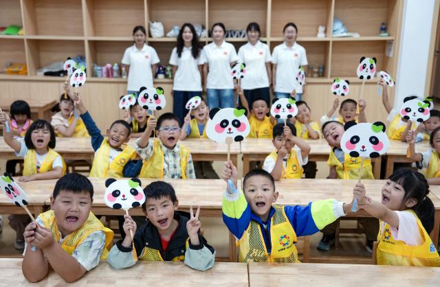 (260815) -- BEIJING, Aug. 15, 2026 (Xinhua) -- Children enrolled in a daycare program show panda-themed fans they made at a teenager activity center in Zhaotong City, southwest China's Yunnan Province, Aug. 14, 2026. This summer vacation the city of Zhaotong introduced a free daycare program for working parents needing workday childcare coverage. Under the program, children will be assisted with their homework, and offered with cultural and sports activities. (Xinhua/Chen Xinbo)