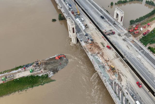 (260815) -- ZHOUKOU, Aug. 15, 2026 (Xinhua) -- An aerial drone photo take on Aug. 15, 2026 shows repair work underway at the site of a levee breach along the Jialu River in Chuanhui District of Zhoukou City, central China's Henan Province. Around 11 p.m. on Thursday, a breach occurred on the east bank embankment of the Jialu River below a bridge in Chuanhui District of Zhoukou City, due to pressure of upstream inflow from the Jialu River and backflow from the Shaying River,.
  Following the breach, multiple rescue teams rushed to the site and launched emergency sealing operation. More than half of the breach has now been sealed. (Xinhua/Hao Yuan)