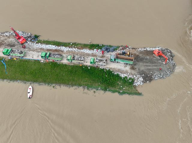 (260815) -- ZHOUKOU, Aug. 15, 2026 (Xinhua) -- An aerial drone photo take on Aug. 15, 2026 shows repair work underway at the site of a levee breach along the Jialu River in Chuanhui District of Zhoukou City, central China's Henan Province. Around 11 p.m. on Thursday, a breach occurred on the east bank embankment of the Jialu River below a bridge in Chuanhui District of Zhoukou City, due to pressure of upstream inflow from the Jialu River and backflow from the Shaying River,.
  Following the breach, multiple rescue teams rushed to the site and launched emergency sealing operation. More than half of the breach has now been sealed. (Xinhua/Hao Yuan)