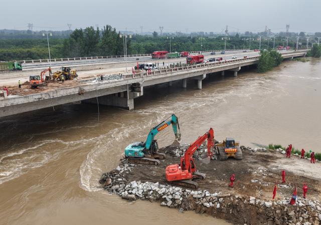 (260815) -- ZHOUKOU, Aug. 15, 2026 (Xinhua) -- A drone photo take on Aug. 15, 2026 shows repair work underway at the site of a levee breach along the Jialu River in Chuanhui District of Zhoukou City, central China's Henan Province. Around 11 p.m. on Thursday, a breach occurred on the east bank embankment of the Jialu River below a bridge in Chuanhui District of Zhoukou City, due to pressure of upstream inflow from the Jialu River and backflow from the Shaying River,.
  Following the breach, multiple rescue teams rushed to the site and launched emergency sealing operation. More than half of the breach has now been sealed. (Xinhua/Hao Yuan)