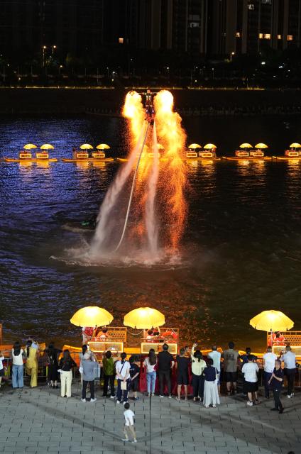 (260815) -- ZHANGJIAJIE, Aug. 15, 2026 (Xinhua) -- Tourists watch a performance at Dayong Ancient Town in Zhangjiajie, central China's Hunan Province, Aug. 14, 2026.
  Leveraging its rich intangible cultural heritage, the city of Zhangjiajie has developed diverse summer getaways and multiple forms of night tours, fueling a travel boom during the peak season. (Xinhua/Dai Mingxuan)