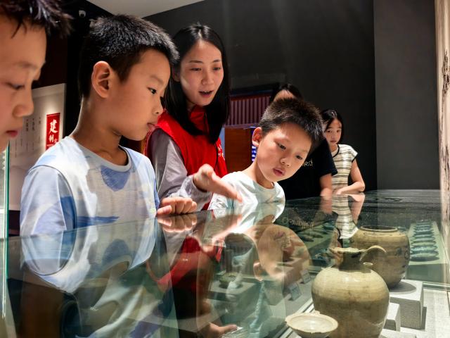 (260815) -- WUHAN, Aug. 15, 2026 (Xinhua) -- A volunteer gives a guided tour to students at Xuan'en County Museum in Xuan'en, central China's Hubei Province, Aug. 15, 2026. Museums in Hubei Province have seen a surging number of children and teenagers on study tours during the summer vacation. With guided tours, hands-on experiences, and intangible cultural heritage classes, these museums are offering more than just exhibitions to enrich the summer life of children and students. (Xinhua/Xiao Yijiu)