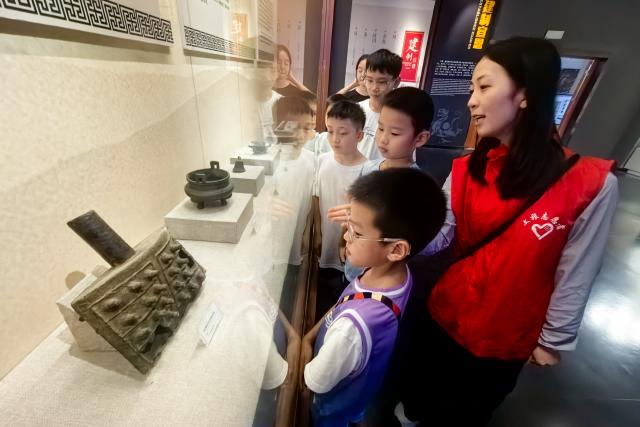 (260815) -- WUHAN, Aug. 15, 2026 (Xinhua) -- A volunteer offers a guided tour to students at Xuan'en County Museum in Xuan'en, central China's Hubei Province, Aug. 15, 2026. Museums in Hubei Province have seen a surging number of children and teenagers on study tours during the summer vacation. With guided tours, hands-on experiences, and intangible cultural heritage classes, these museums are offering more than just exhibitions to enrich the summer life of children and students. (Xinhua/Xiao Yijiu)