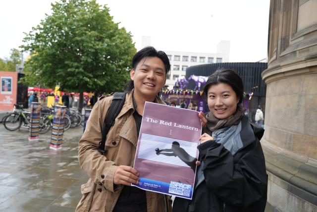(260815) -- EDINBURGH, Aug. 15, 2026 (Xinhua) -- Fan Shaolun (L) and Liang Yumin, creators of Chinese-language solo play "The Red Lantern," pose for photos with a poster of their play in Edinburgh, Britain, Aug. 9, 2026. TO GO WITH "Feature: Chinese theater artists bring WWII Chongqing story to Edinburgh stage" (Xinhua/Zhao Jiasong)