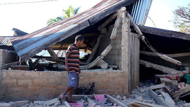 (260815) -- JAKARTA, Aug. 15, 2026 (Xinhua) -- A man stands near a damaged house after an earthquake on Flores Island, Indonesia, on Aug. 15, 2026. The death toll from a 7.7-magnitude earthquake and several strong aftershocks that struck off the coast of Flores Island in eastern Indonesia has risen to 47, the country's National Disaster Mitigation Agency (BNPB) said Saturday. (Photo by Arifin/Xinhua)