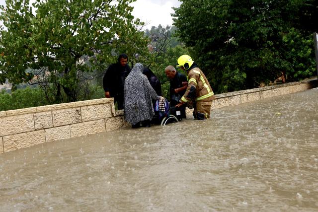 (260815) -- JERUSALEM, Aug. 15, 2026 (Xinhua) -- Rescuers help a man out of a flooded street in Jerusalem, Aug. 15, 2026. Rare heavy downpours trigger mountain flash floods and urban waterlogging across Jerusalem on Saturday. The region is currently in midsummer, a period typically marked by extreme drought and almost zero precipitation. (Photo by Jamal Awad/Xinhua)