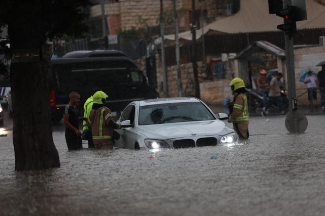 (260815) -- JERUSALEM, Aug. 15, 2026 (Xinhua) -- Rescuers try to help a stranded car out of a flooded road in Jerusalem, Aug. 15, 2026. Rare heavy downpours trigger mountain flash floods and urban waterlogging across Jerusalem on Saturday. The region is currently in midsummer, a period typically marked by extreme drought and almost zero precipitation. (Photo by Jamal Awad/Xinhua)