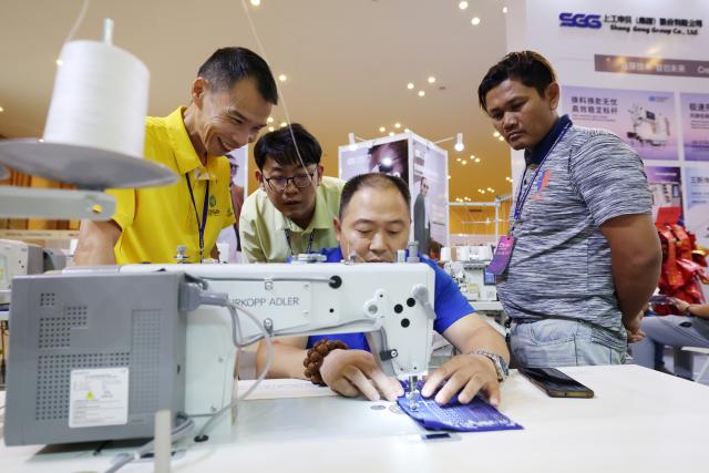 (260816) -- PHNOM PENH, Aug. 16, 2026 (Xinhua) -- A man tries a sewing machine during an international industrial expo in Phnom Penh, Cambodia, Aug. 15, 2026. A wide variety of advanced Chinese tech and manufacturing firms showcased cutting-edge machinery, automation, and innovative production solutions at a major international industrial exhibition here in Cambodia's capital. (Photo by Sovannara/Xinhua)