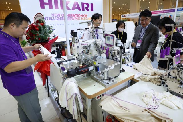(260816) -- PHNOM PENH, Aug. 16, 2026 (Xinhua) -- People look at sewing machines during an international industrial expo in Phnom Penh, Cambodia, Aug. 15, 2026. A wide variety of advanced Chinese tech and manufacturing firms showcased cutting-edge machinery, automation, and innovative production solutions at a major international industrial exhibition here in Cambodia's capital. (Photo by Sovannara/Xinhua)