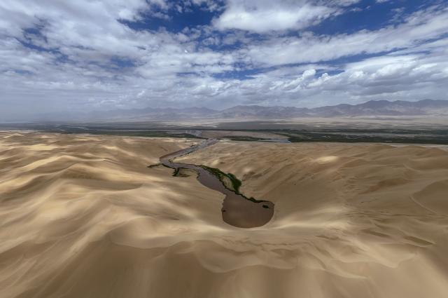 (260816) -- RUOQIANG, Aug. 16, 2026 (Xinhua) -- A drone photo taken on Aug. 10, 2026 shows a view of the Altun Mountain National Nature Reserve in northwest China's Xinjiang Uygur Autonomous Region. Averaging 4,500 meters in elevation, the Altun Mountain National Nature Reserve, a 45,000-square-kilometer haven situated in the southeastern corner of Xinjiang, is subject to harsh environmental conditions. 
   In early August, a patrol team comprising nature reserve staff, local township officials and police officers ventured into this remote plateau wilderness for a monthly routine patrol.  
   Bumping along a dry river valley winding through the mountains, the team members checked for suspicious signs, observed wildlife, and maintained management station facilities. They conducted routine inspections within the reserve supported by advanced technological equipment, including high-altitude surveillance cameras, infrared cameras and drones. Their main mission was to curb illegal activities to ensure protection of one of China's most remote and ecologically vital sanctuaries. 
  At nearly 4,800 meters above sea level, almost every member of the team suffered from altitude sickness like headaches and insomnia, but their firm conviction to protect this reserve gave them strength to overcome challenges and carry on with their work. 
  Established in 1983, the reserve is managed by a team of about 70 people. Over the past 40 years, generation after generation of patrollers have devoted themselves to protecting this land with stark contrasts and rich biodiversity. (Xinhua/Hu Huhu)