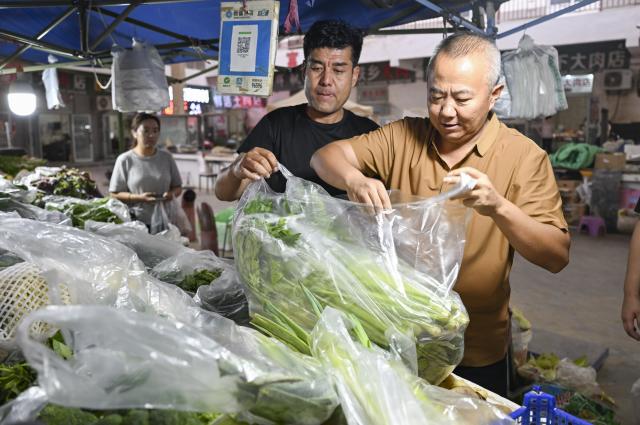 (260816) -- RUOQIANG, Aug. 16, 2026 (Xinhua) -- Rangers Chen Wei (R) and Yusupjan Sulayman buy vegetables at a market in Ruoqiang County before starting their inspection work bound for the Altun Mountain National Nature Reserve in northwest China's Xinjiang Uygur Autonomous Region, on Aug. 6, 2026. Averaging 4,500 meters in elevation, the Altun Mountain National Nature Reserve, a 45,000-square-kilometer haven situated in the southeastern corner of Xinjiang, is subject to harsh environmental conditions. 
   In early August, a patrol team comprising nature reserve staff, local township officials and police officers ventured into this remote plateau wilderness for a monthly routine patrol.  
   Bumping along a dry river valley winding through the mountains, the team members checked for suspicious signs, observed wildlife, and maintained management station facilities. They conducted routine inspections within the reserve supported by advanced technological equipment, including high-altitude surveillance cameras, infrared cameras and drones. Their main mission was to curb illegal activities to ensure protection of one of China's most remote and ecologically vital sanctuaries. 
  At nearly 4,800 meters above sea level, almost every member of the team suffered from altitude sickness like headaches and insomnia, but their firm conviction to protect this reserve gave them strength to overcome challenges and carry on with their work. 
  Established in 1983, the reserve is managed by a team of about 70 people. Over the past 40 years, generation after generation of patrollers have devoted themselves to protecting this land with stark contrasts and rich biodiversity. (Xinhua/Hu Huhu)