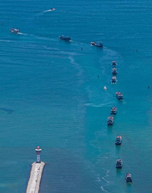 (260816) -- QIONGHAI, Aug. 16, 2026 (Xinhua) -- An aerial drone photo taken on Aug. 16, 2026 shows fishing boats departing for fishing from Tanmen port in Qionghai, south China's Hainan Province. The fishing season of the South China Sea kicked off at noon on Sunday after this summer's three-and-a-half-month fishing ban. (Xinhua/Pu Xiaoxu)