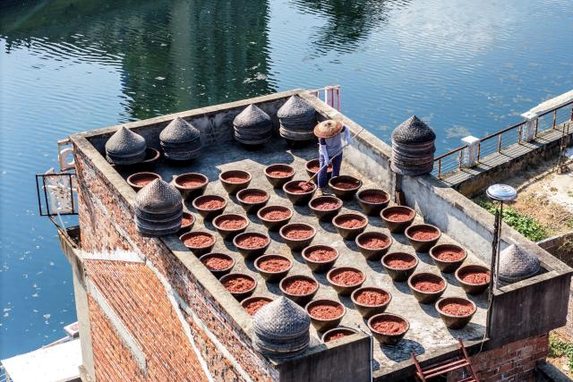 (260816) -- SHUANGFENG, Aug. 16, 2026 (Xinhua) -- A resident airs chili sauce on a rooftop in Yongfeng Subdistrict of Shuangfeng County, Loudi City of central China's Hunan Province, Aug. 16, 2026. As one of China's protected geographical indication products, chili sauce made in Yongfeng Subdistrict boasts a history of several centuries. (Photo by Li Jianxin/Xinhua)