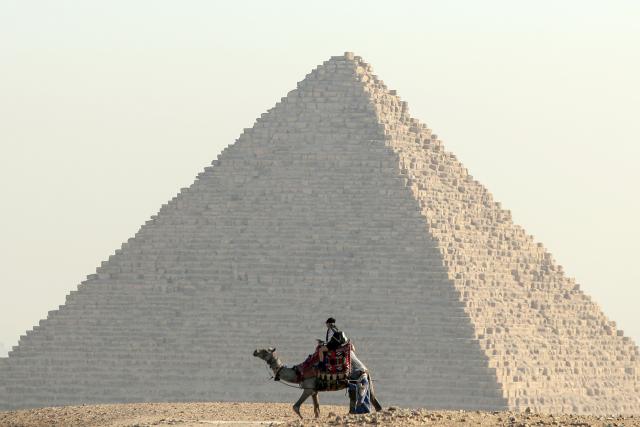 (260816) -- GIZA, Aug. 16, 2026 (Xinhua) -- A tourist rides camels at the Pyramids scenic spot in Giza, Egypt, Aug. 16, 2026. (Xinhua/Ahmed Gomaa)