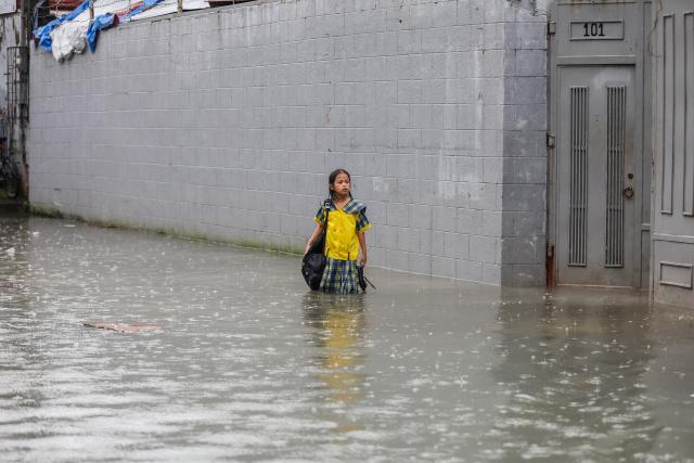 (260817) -- QUEZON CITY, Aug. 17, 2026 (Xinhua) -- A student stands in floodwater in Quezon City, the Philippines, on Aug. 17, 2026. The Philippine government has suspended in-person classes in Metro Manila and 12 other provinces as heavy rains from tropical cyclones and the southwest monsoon continue to batter the country, local media reported on Monday.
   The extreme rainfall has triggered severe flooding and landslides across the nation. The well-known flood-control corruption scandal has left key infrastructure unfinished or poorly maintained, further straining the country's disaster response, local media reported. (Xinhua/Rouelle Umali)