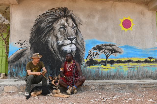 (260817) -- NAROK, Aug. 17, 2026 (Xinhua) -- Zhuo Qiang (L) talks with Simon Msago, a Maasai community leader in Ngoswani, in Narok, Kenya, Aug. 12, 2026. As dawn breaks over Ol Kinyei Conservancy in Kenya's Maasai Mara ecosystem, rangers are already combing the grasslands for signs of unauthorized entry and poaching while keeping a close watch on wildlife. Among them is Chinese conservationist Zhuo Qiang, nicknamed "Simba," the Swahili word for lion. For him, this early-morning routine is driven by a broader mission to achieve human-wildlife coexistence.TO GO WITH "Feature: Chinese conservationist explores community-based wildlife protection in Kenya" (Xinhua/Liu Qiong)