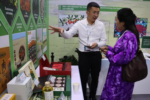 (260818) -- ULAN BATOR, Aug. 18, 2026 (Xinhua) -- A staff member speaks with a visitor at the exhibition area of the "China Corner" in the Blue Zone of the 17th Session of the Conference of the Parties (COP17) to the United Nations Convention to Combat Desertification (UNCCD) in Ulan Bator, Mongolia, Aug. 17, 2026. The "China Corner" themed exhibition made its debut on Monday, showcasing China's experience and achievements in combating desertification. (Xinhua/Bolortsetseg)