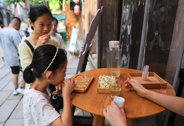 (260818) -- FUZHOU, Aug. 18, 2026 (Xinhua) -- Children taste jasmine tea at the Shangxiahang historical and cultural block in Fuzhou, southeast China's Fujian Province, Aug. 17, 2026. Jasmine tea is tea scented with the aroma of jasmine blossoms and typically has green tea as its base. The Jasmine tea scenting techniques of Fuzhou have been enlisted as a state-level intangible cultural heritage in China.
  In recent years, businesses in Fuzhou have built on the traditional tea culture while developing innovative jasmine tea inspired product categories such as beverages, desserts and daily-use items. Meanwhile, the city has rolled out measures to promote jasmine tea brands and the integration of tea culture and tourism, aiming to stimulate cultural and tourism consumption. (Xinhua/Du Xiaoyi)