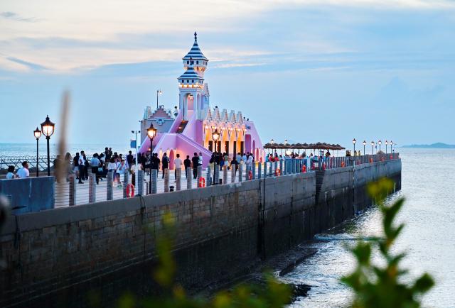 (260818) -- HUI'AN, Aug. 18, 2026 (Xinhua) -- People visit the Chongwu ancient ferry terminal scenic area in Hui'an County of Quanzhou, southeast China's Fujian Province, Aug. 17, 2026. The Chongwu ancient ferry terminal covers an area of 33 mu (about 2.2 hectares) in Hui'an County of southeast China's Fujian Province. In 2024, local authorities transformed it from an idle terminal into a coastal vacation destination that integrates art galleries, a pier runway, trendy restaurants, and family playgrounds. (Xinhua/Lin Shanchuan)