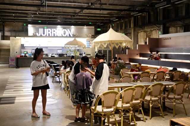 (260818) -- HUI'AN, Aug. 18, 2026 (Xinhua) -- People enjoy themselves inside an art space, which is transformed from an idle warehouse, at the Chongwu ancient ferry terminal scenic area in Hui'an County of Quanzhou, southeast China's Fujian Province, Aug. 17, 2026. The Chongwu ancient ferry terminal covers an area of 33 mu (about 2.2 hectares) in Hui'an County of southeast China's Fujian Province. In 2024, local authorities transformed it from an idle terminal into a coastal vacation destination that integrates art galleries, a pier runway, trendy restaurants, and family playgrounds. (Xinhua/Lin Shanchuan)