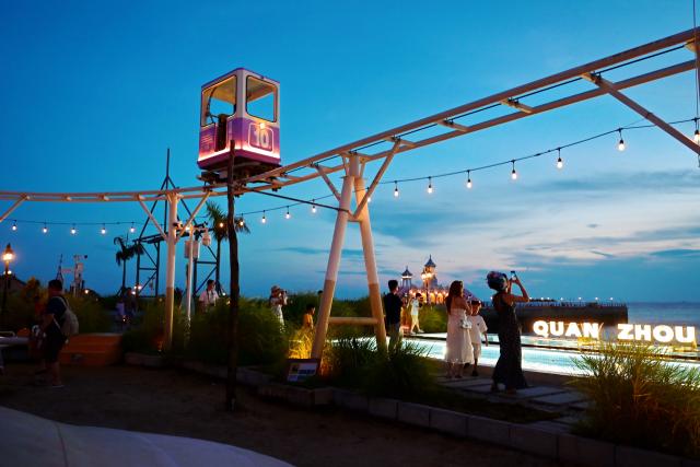 (260818) -- HUI'AN, Aug. 18, 2026 (Xinhua) -- People enjoy a night view at the Chongwu ancient ferry terminal scenic area in Hui'an County of Quanzhou, southeast China's Fujian Province, Aug. 17, 2026. The Chongwu ancient ferry terminal covers an area of 33 mu (about 2.2 hectares) in Hui'an County of southeast China's Fujian Province. In 2024, local authorities transformed it from an idle terminal into a coastal vacation destination that integrates art galleries, a pier runway, trendy restaurants, and family playgrounds. (Xinhua/Lin Shanchuan)