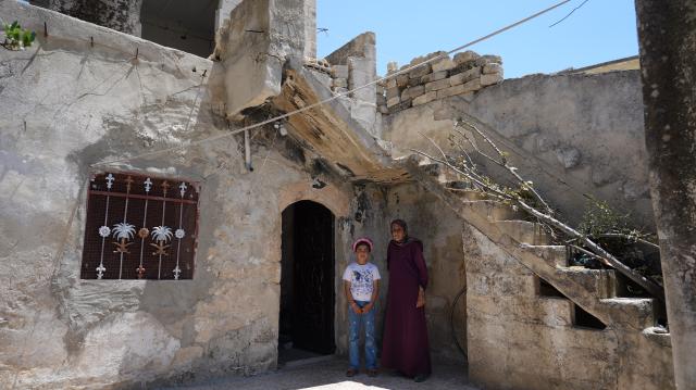 (260818) -- QALAAT AL-MADIQ, Aug. 18, 2026 (Xinhua) -- Sultana al-Sheikh Ibrahim (R), 80, and her granddaughter stand at their war-damaged home inside Qalaat al-Madiq in Hama province, central Syria, June 24, 2026.
  TO GO WITH "Letter from Mideast: In a Syrian castle, a laurel still stands" (Photo by Monsef Memari/Xinhua)