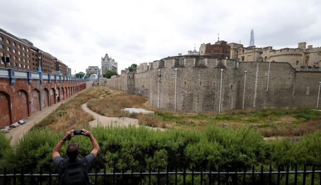 (260818) -- LONDON, Aug. 18, 2026 (Xinhua) -- A man takes photos of the dry garden outside the Tower of London, turned yellow-brown due to dryness, in London, Britain, on Aug. 18, 2026. In Britain, extreme dryness becomes a defining feature of the summer. Provisional data from the Met Office showed that England and Wales experienced their driest July on record, while nearly three-quarters of England was officially under drought conditions by Aug. 10. (Xinhua/Li Ying)