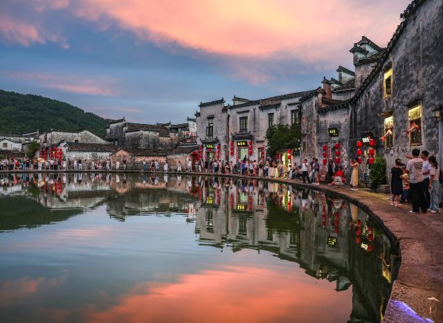 (260819) -- HUANGSHAN, Aug. 19, 2026 (Xinhua) -- Tourists visit a pond at dusk in Hongcun Village, Yixian County of Huangshan City, east China's Anhui Province, Aug. 18, 2026. (Xinhua/Chang Nengjia)