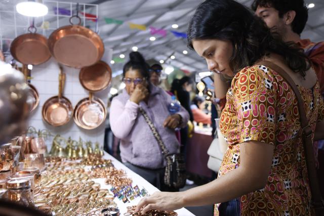 (260819) -- MEXICO CITY, Aug. 19, 2026 (Xinhua) -- Visitors select copper accessories during the 12th Indigenous Cultures Festival at Constitution Square in Mexico City, capital of Mexico, Aug. 18, 2026. Inside a large exhibition tent, visitors browse goods and taste local specialty drinks, while artisans demonstrate traditional skills such as embroidery. The festival will run until Aug. 23. (Xinhua/Liu Wenhui)