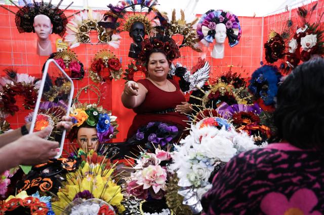 (260819) -- MEXICO CITY, Aug. 19, 2026 (Xinhua) -- A vendor introduces handmade headdresses to a visitor during the 12th Indigenous Cultures Festival at Constitution Square in Mexico City, capital of Mexico, Aug. 18, 2026. Inside a large exhibition tent, visitors browse goods and taste local specialty drinks, while artisans demonstrate traditional skills such as embroidery. The festival will run until Aug. 23. (Xinhua/Liu Wenhui)