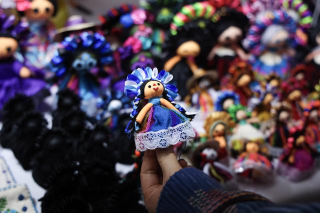 (260819) -- MEXICO CITY, Aug. 19, 2026 (Xinhua) -- A visitor holds a handmade cloth doll during the 12th Indigenous Cultures Festival at Constitution Square in Mexico City, capital of Mexico, Aug. 18, 2026. Inside a large exhibition tent, visitors browse goods and taste local specialty drinks, while artisans demonstrate traditional skills such as embroidery. The festival will run until Aug. 23. (Xinhua/Liu Wenhui)